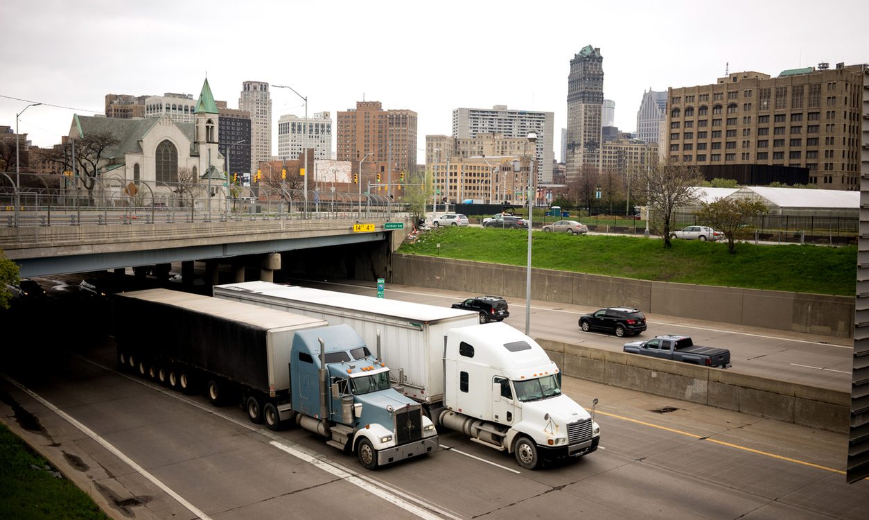 Tractor trailers on a freeway beneath a city skyline