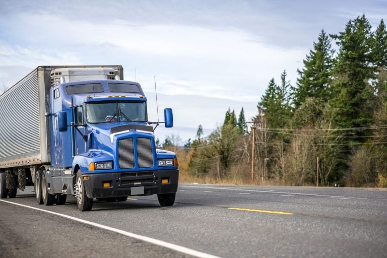 Semi truck with a van trailer on a rural highway