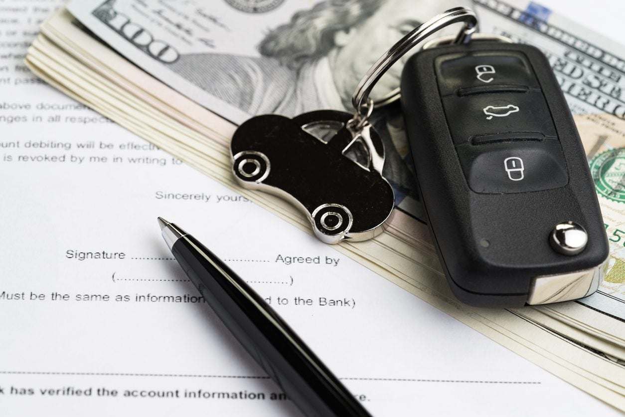 Car key and cash resting on a signed agreement