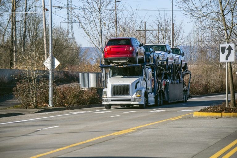 Open car hauler loaded on both decks running a divided highway