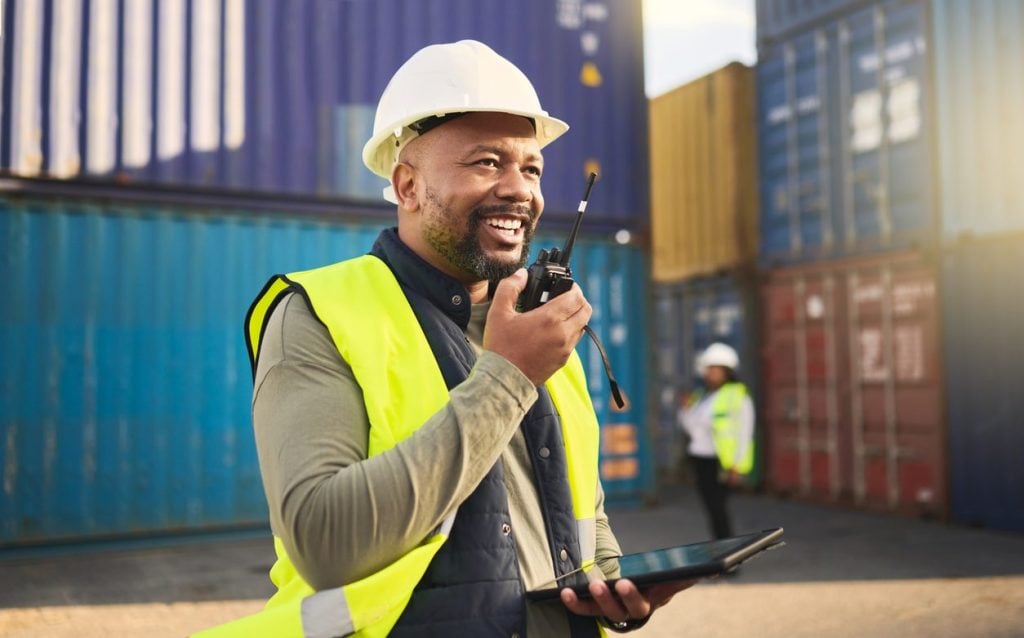 Logistics worker with a radio and tablet in a container yard