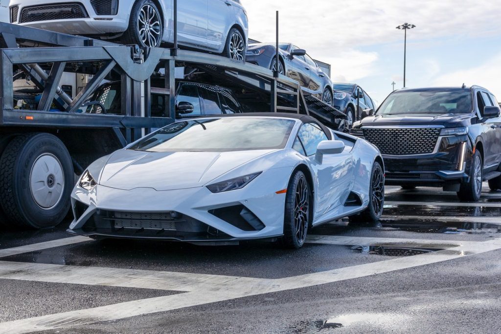 Low clearance sports car on the ground beside a loaded car hauler