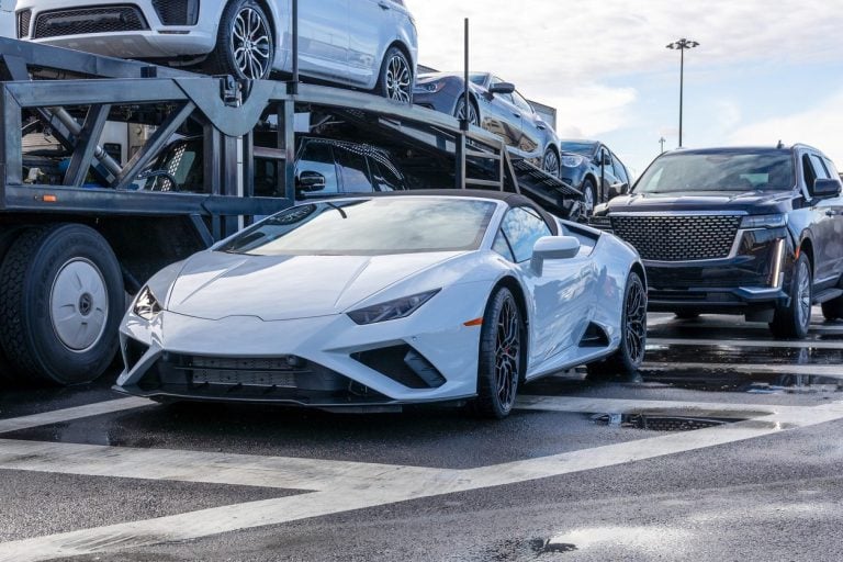 Low clearance sports car on the ground beside a loaded car hauler