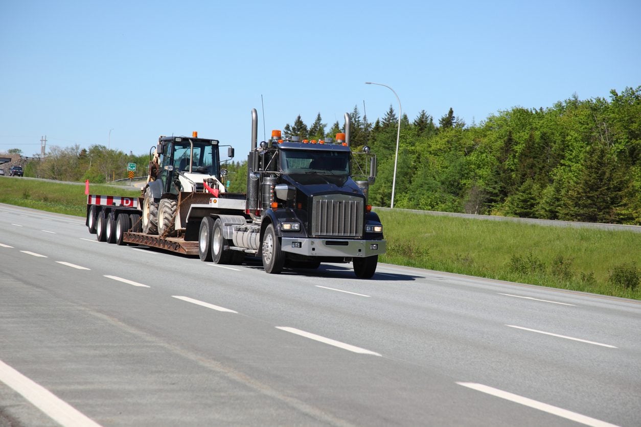 Conventional tractor hauling a tracked machine on a lowboy trailer