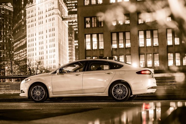 White luxury sedan on a city street at night