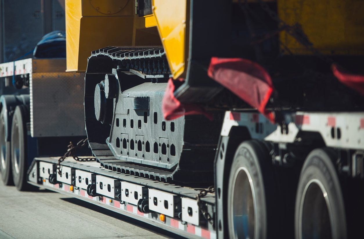 Tracked machine chained down on a lowboy trailer deck