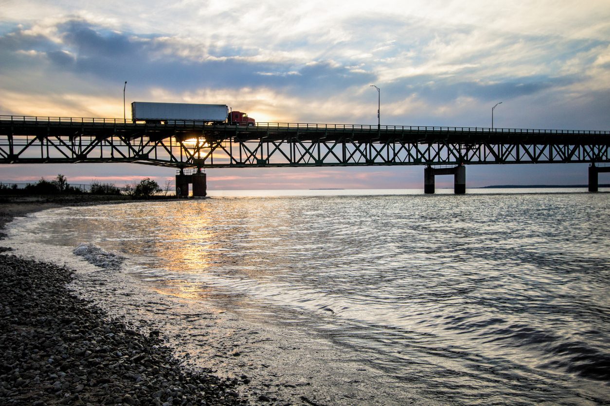 Semi truck crossing a long suspension bridge over water