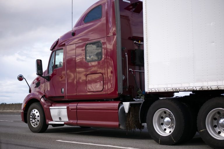 Maroon conventional sleeper tractor with a trailer