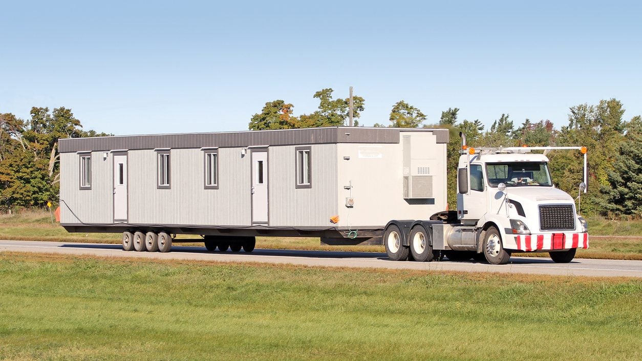 Semi truck hauling a modular building unit along a highway