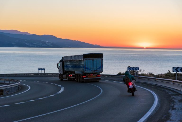 Motorcycle and truck on a coastal highway at sunset