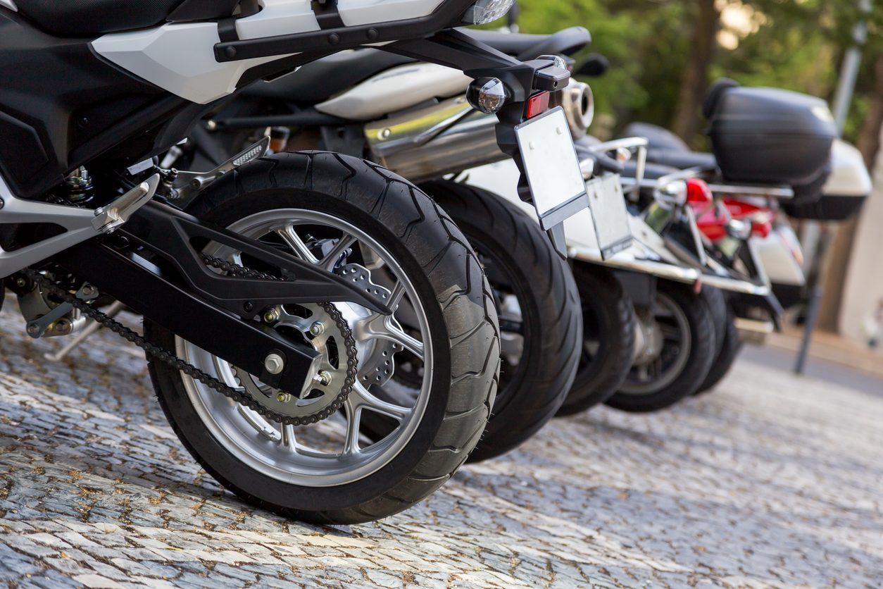 Rear wheels and exhausts of motorcycles parked in a row