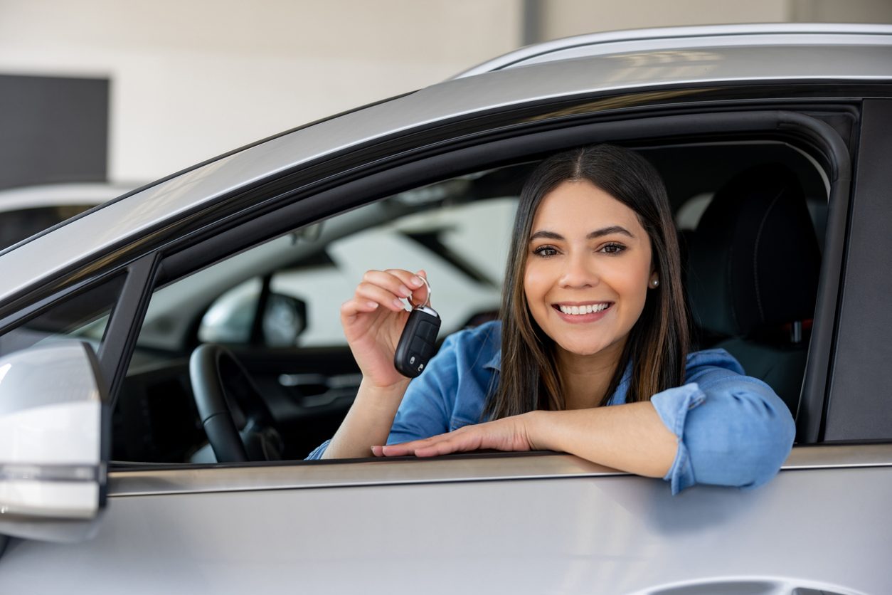 Driver holding the keys of a new car at a dealership