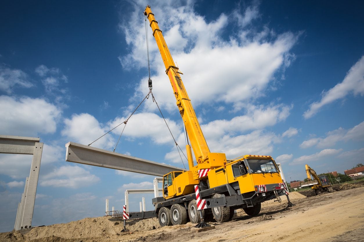 Mobile crane lifting a beam on a job site