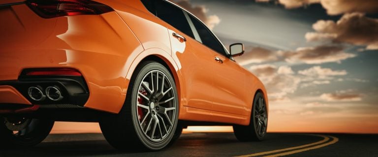 Rear quarter view of an orange performance car at sunset