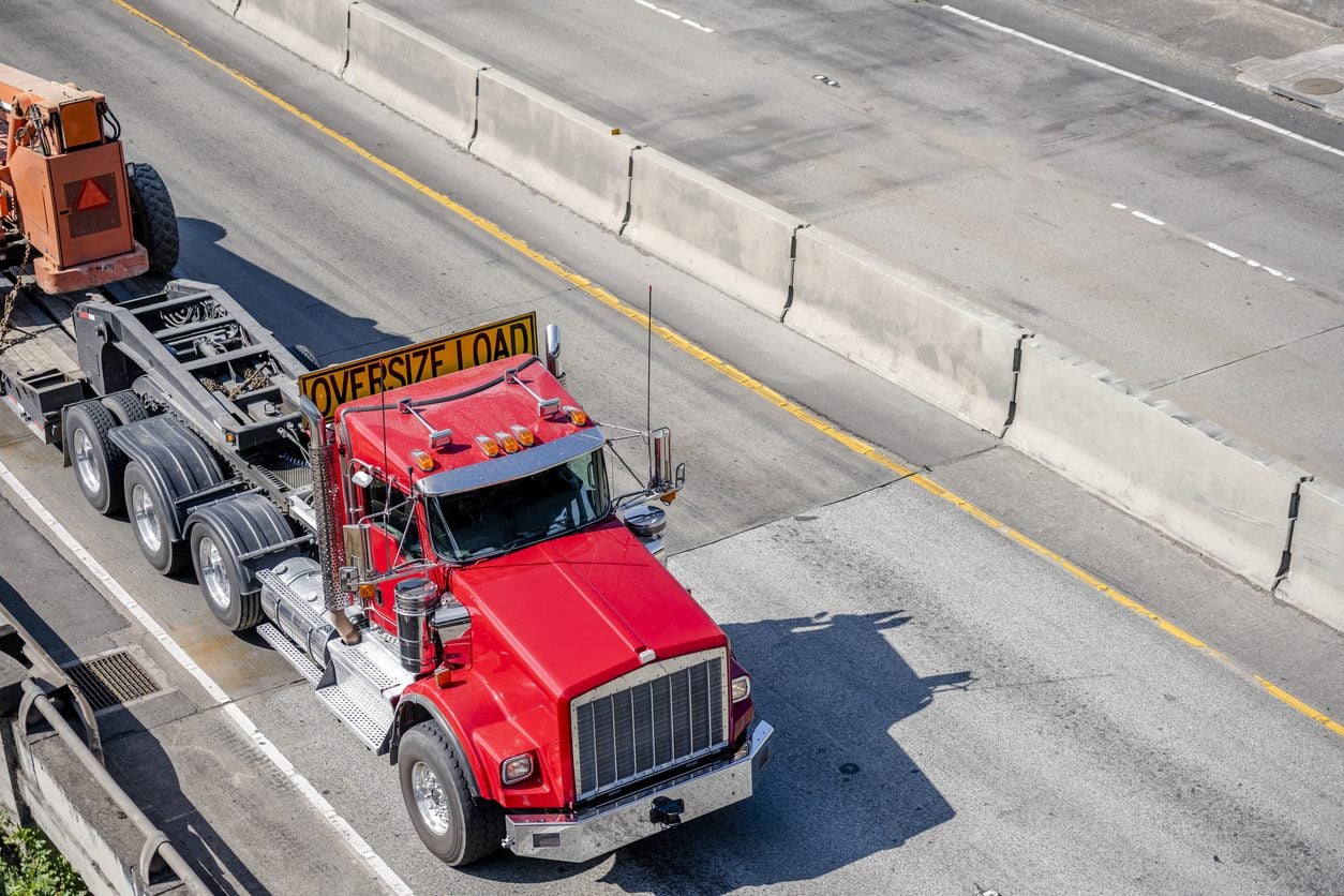 Oversize load truck hauling equipment on a lowboy trailer