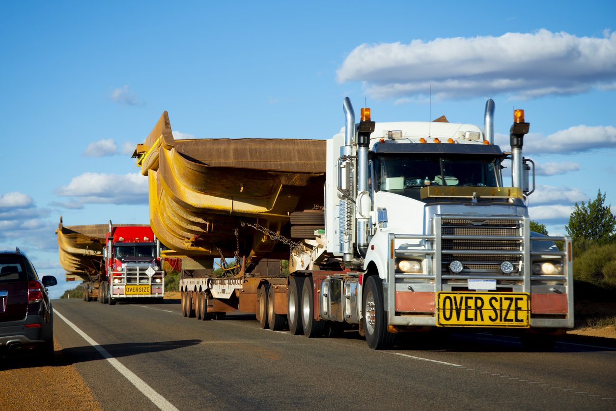 Oversize load convoy carrying heavy machinery on a highway