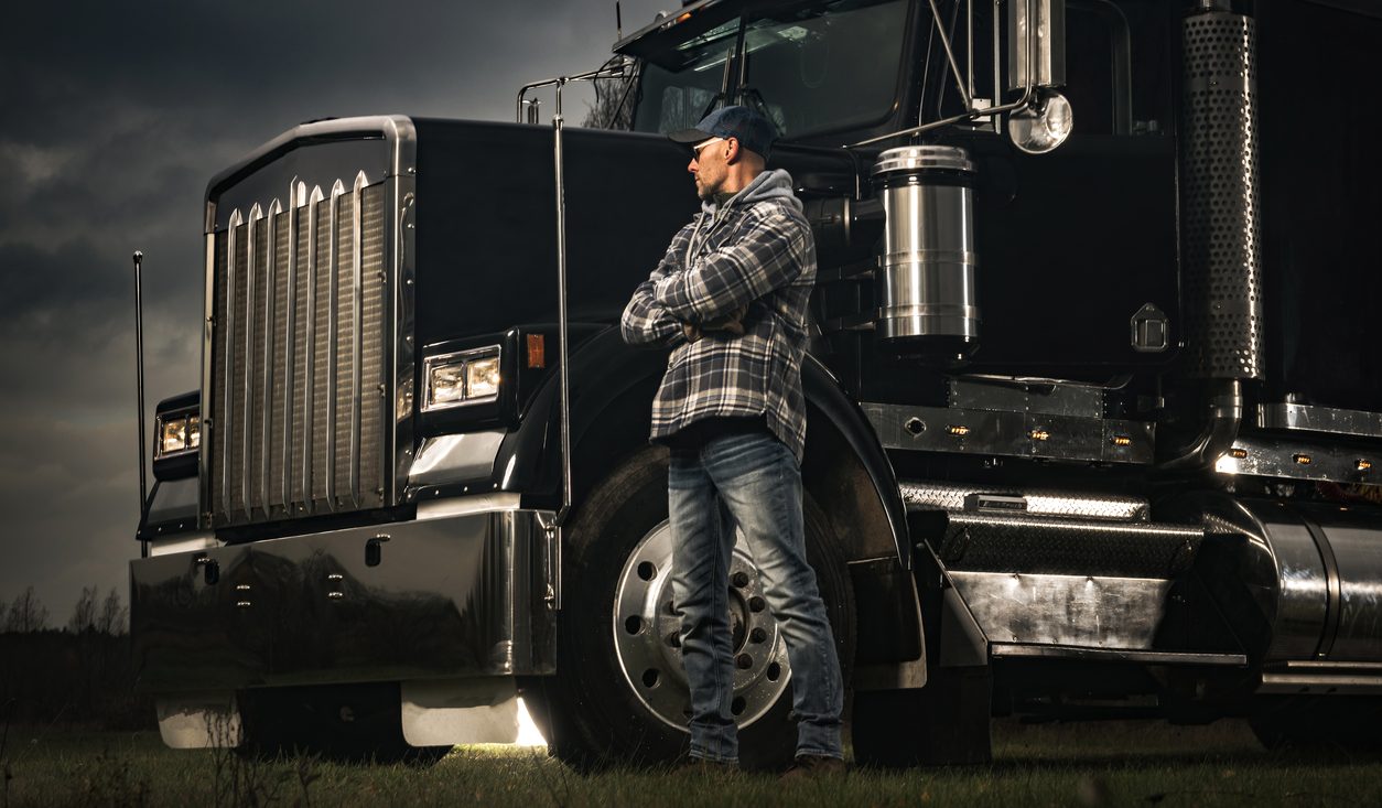 Owner operator standing beside his conventional tractor