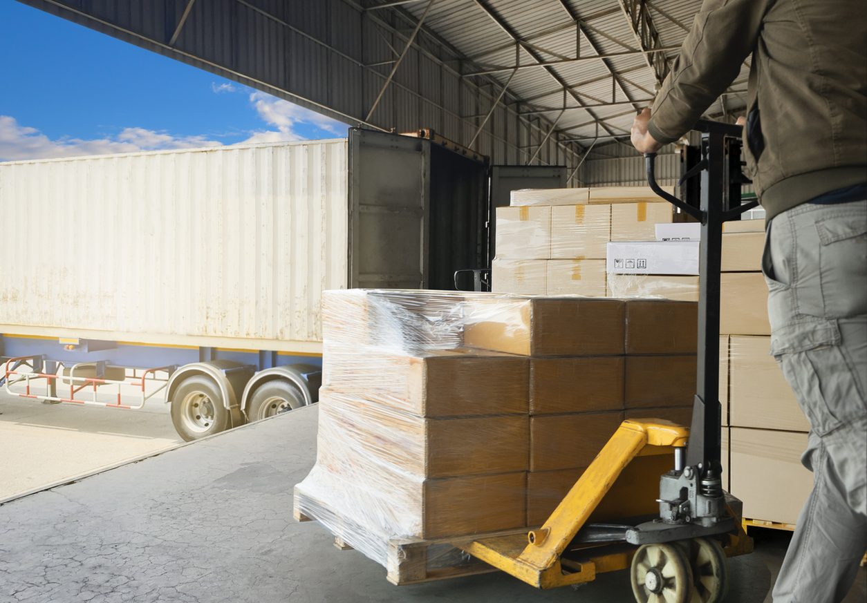 Worker moving a wrapped pallet into a trailer
