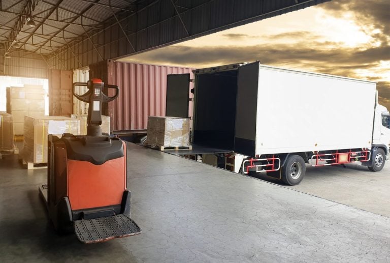 Pallet truck beside a box truck at a warehouse dock
