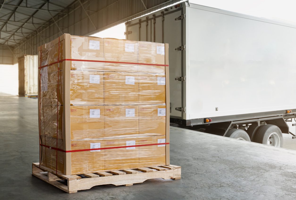 Banded pallet of freight waiting beside a box truck