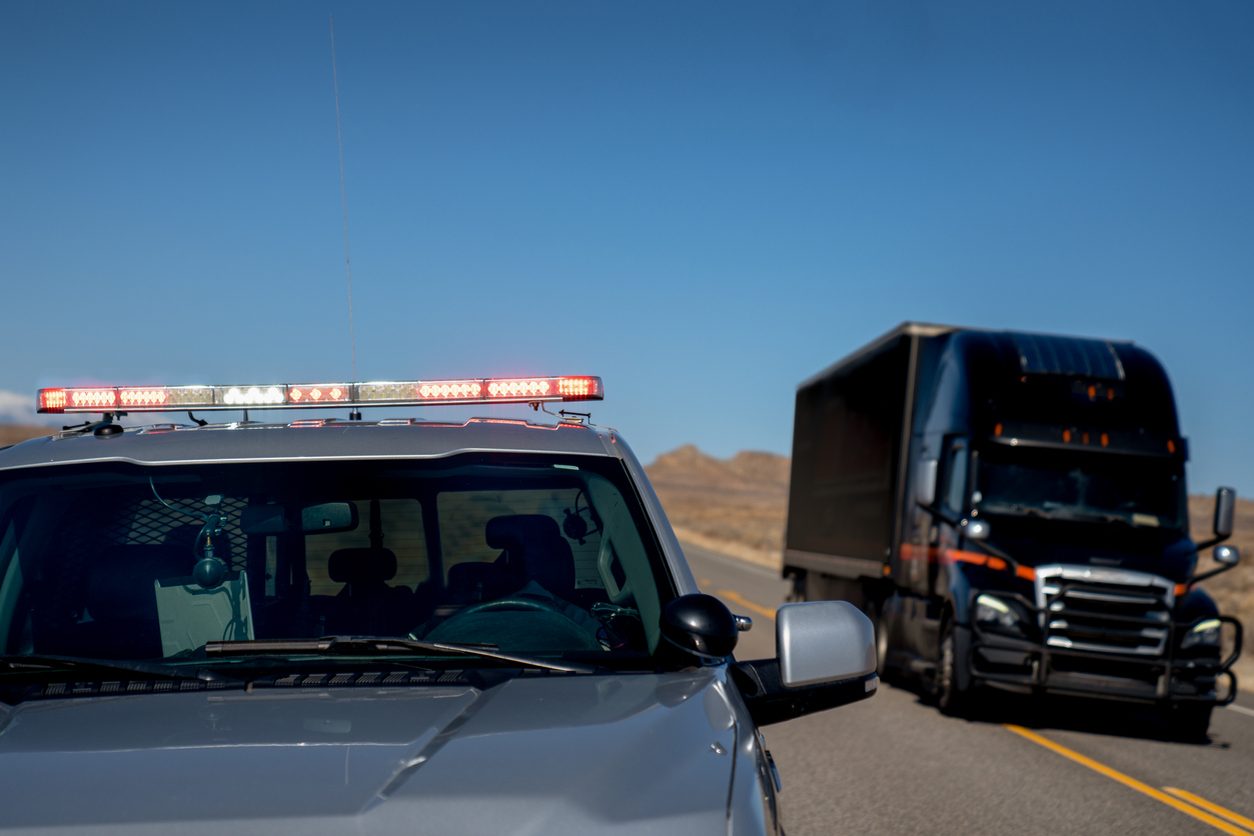 Highway patrol car with its lights on beside a semi truck
