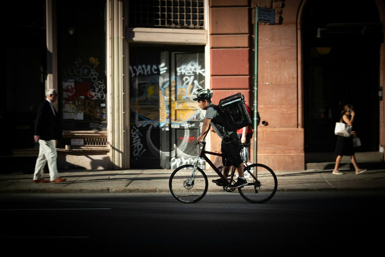 Bike courier with a delivery backpack crossing a city street