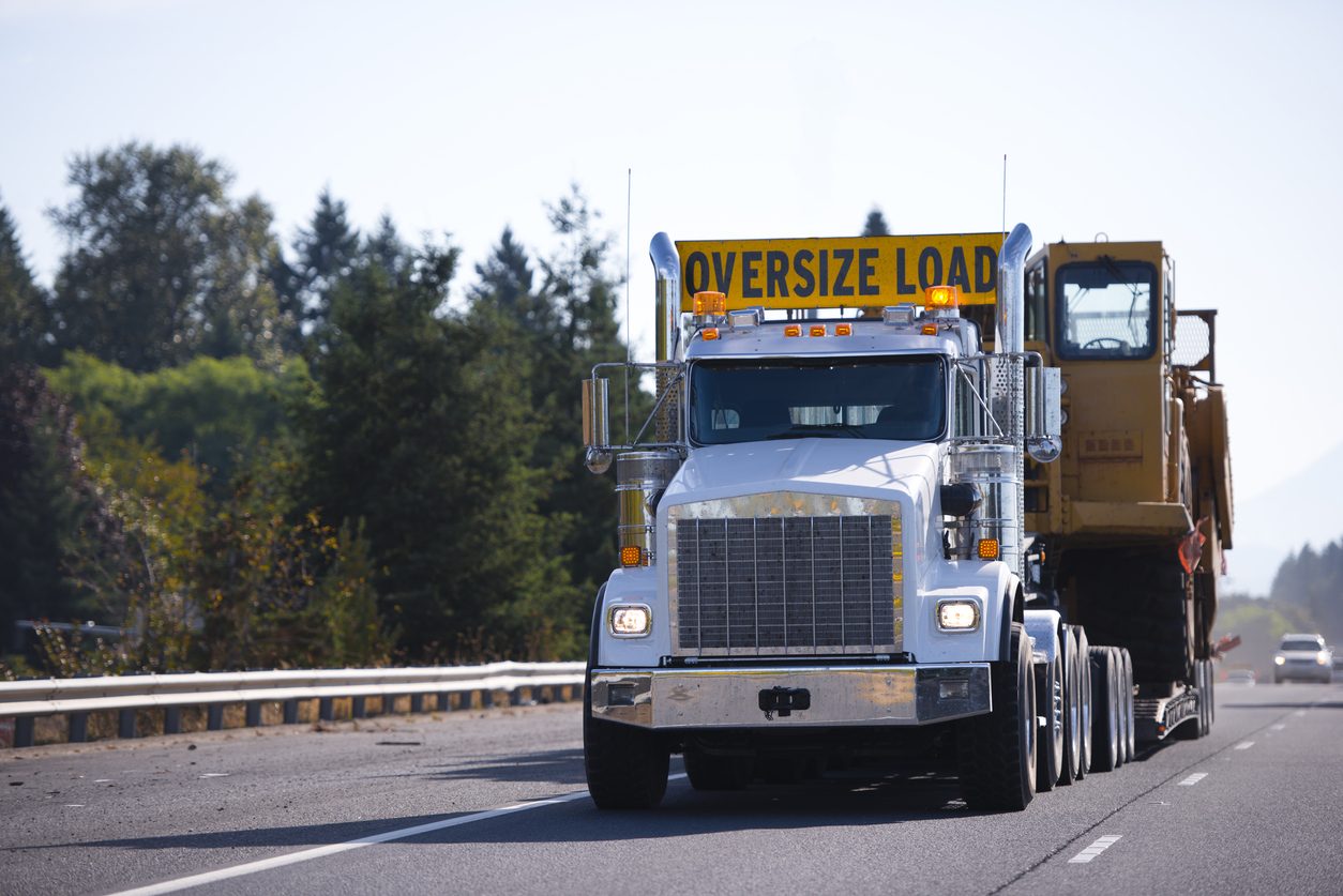 Oversize permit load carrying a dump body on a step deck