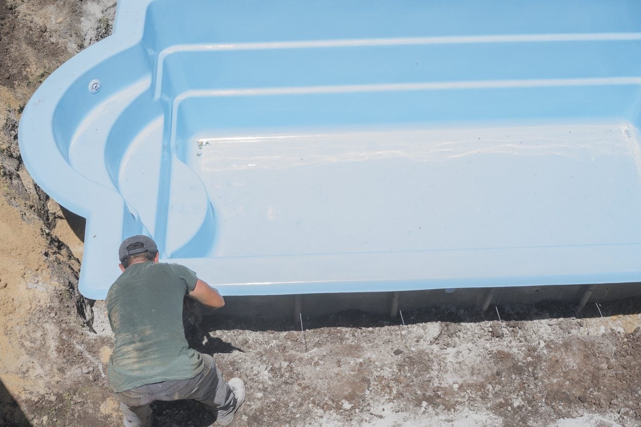Fiberglass pool shell being set into an excavation