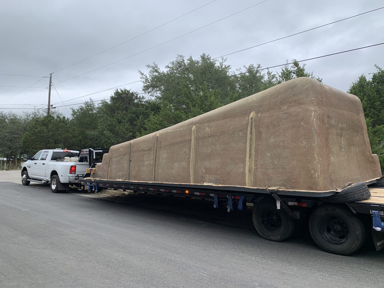 Fiberglass pool shell inverted on a flatbed trailer
