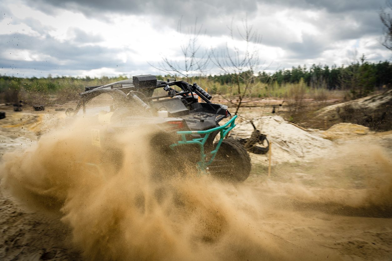 Quad bike throwing up sand on a dirt track