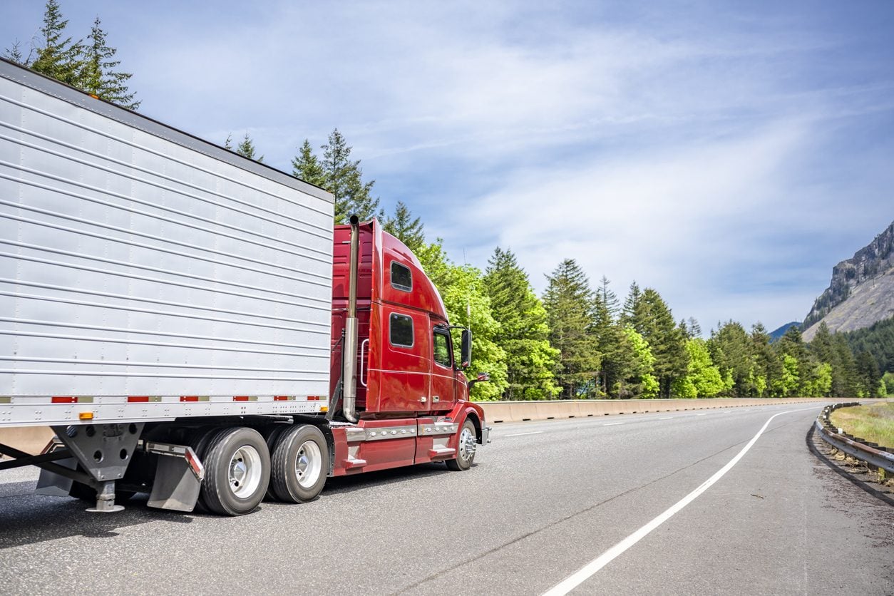 Red conventional tractor with a refrigerated trailer on a highway