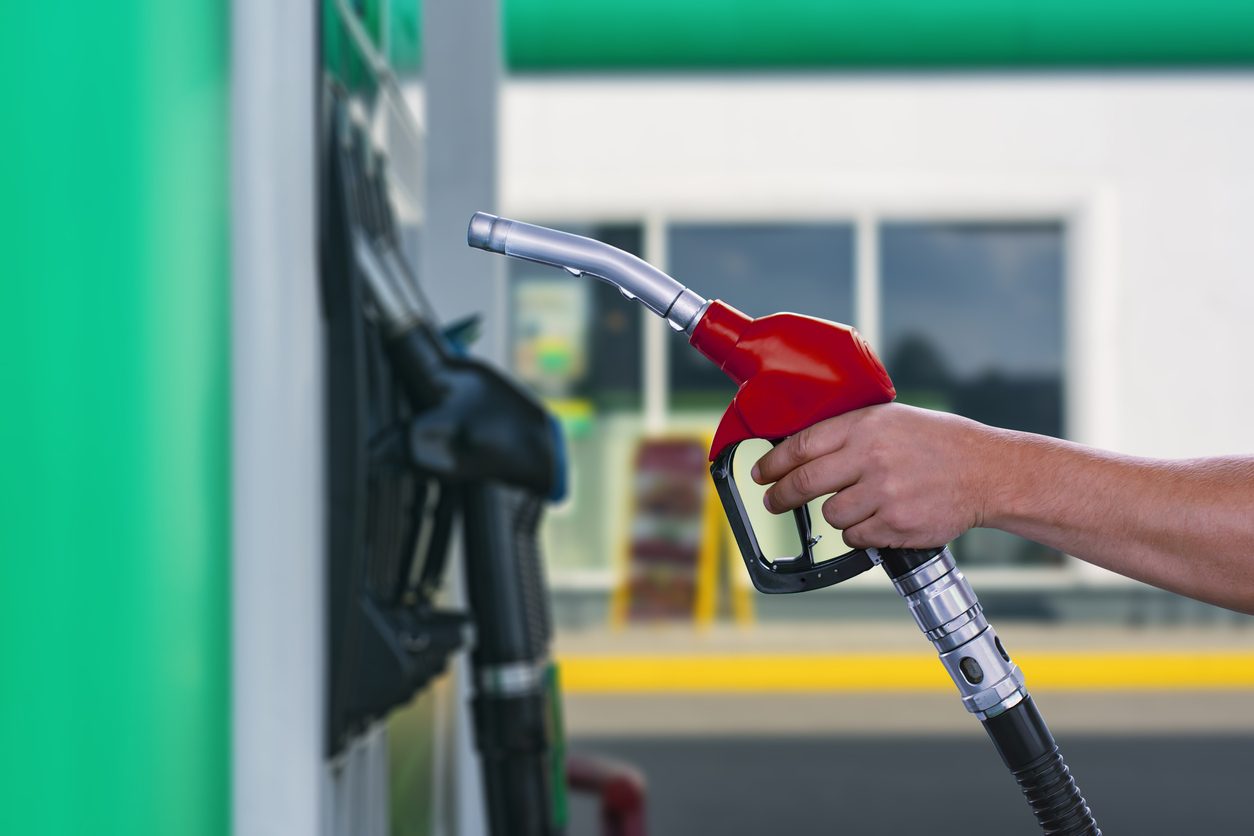 Hand holding a fuel nozzle at a service station pump