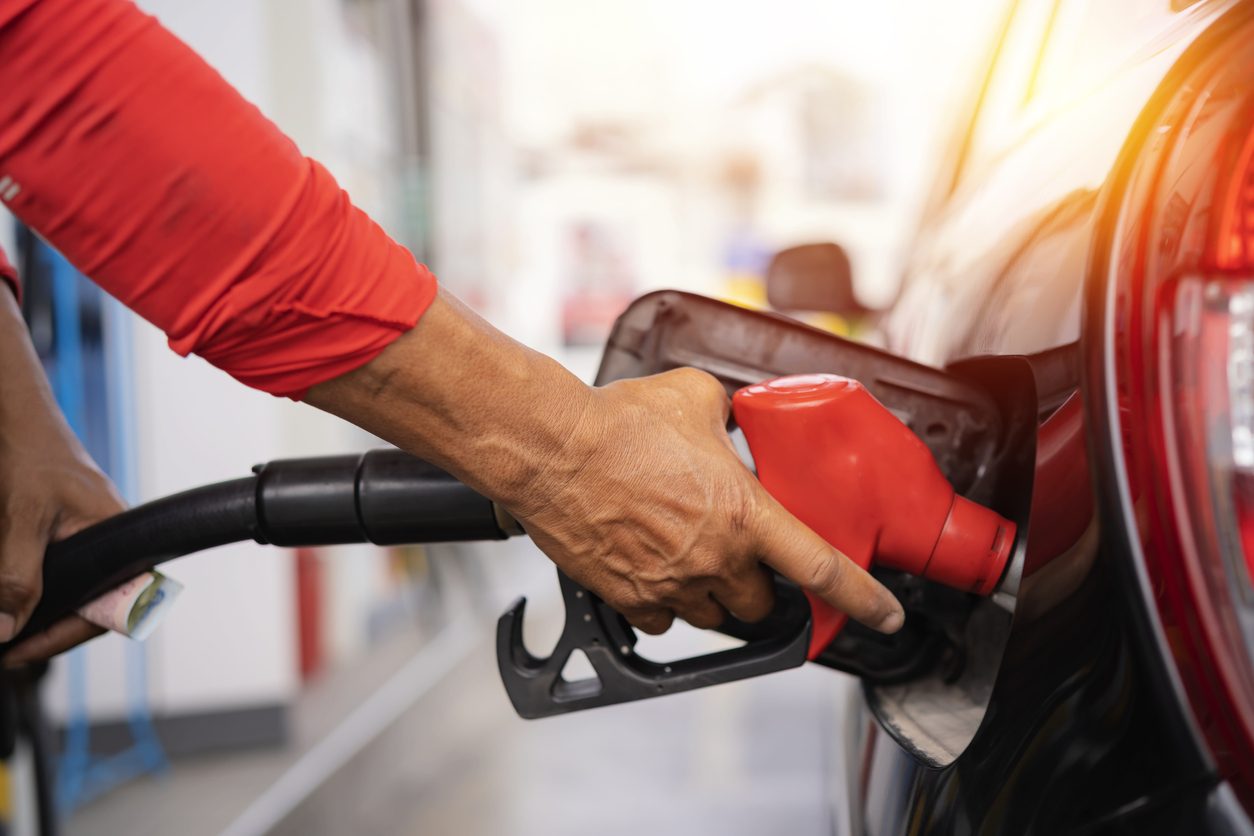 Person refueling a red car at a gas station pump