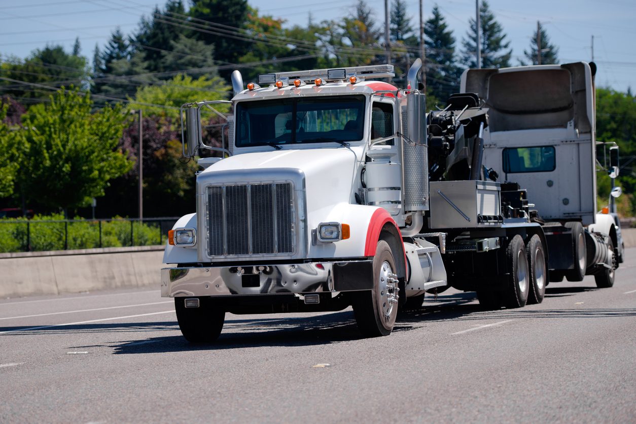 Conventional tractor towing a disabled truck