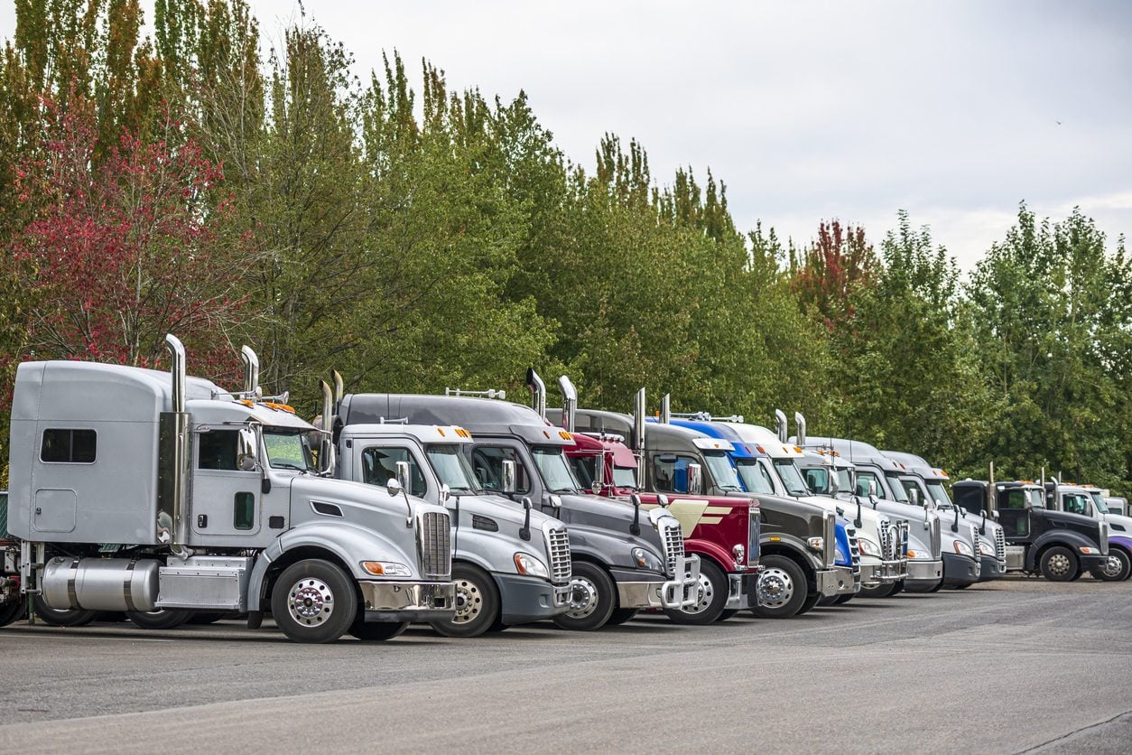 Row of conventional tractors parked at a yard