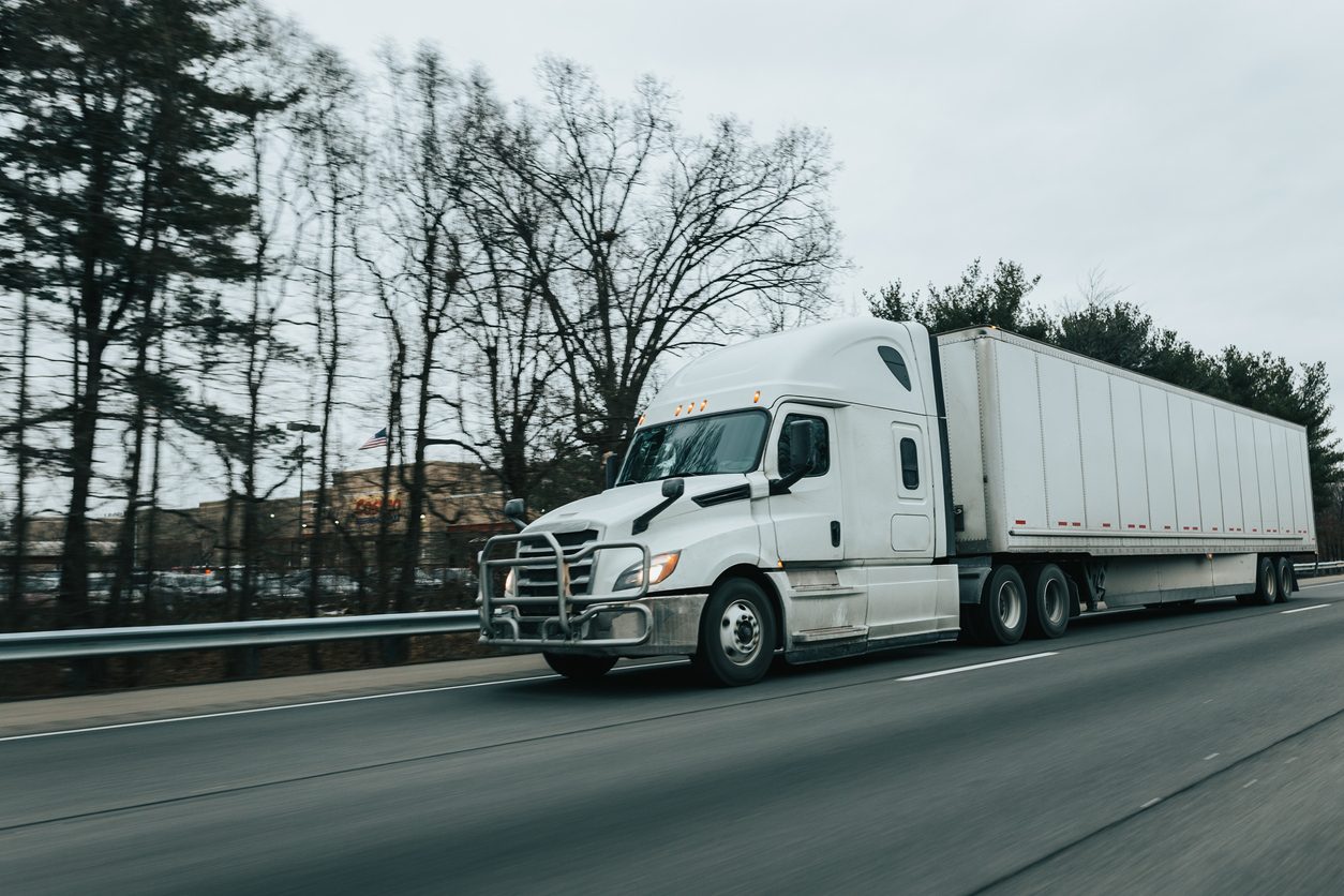 Semi truck running a highway between towns