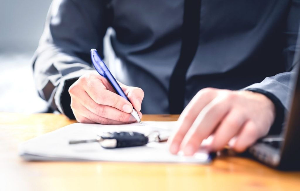 Signing a vehicle transport contract with a car key on the desk