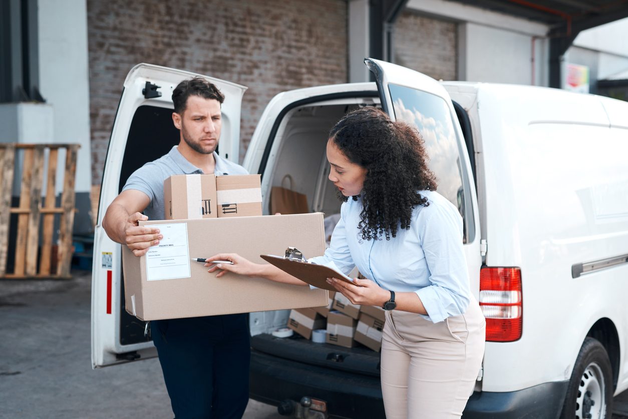 Checking boxes onto a delivery van outside a small business