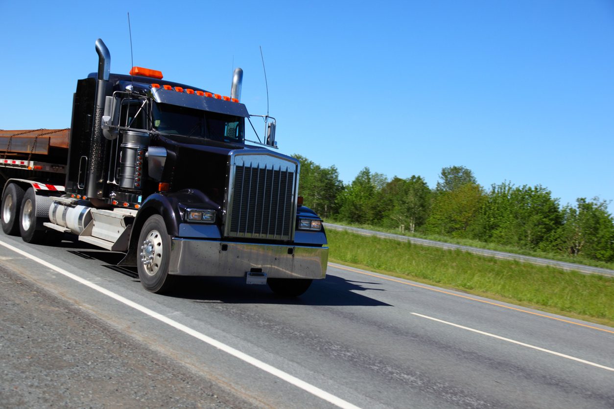 Conventional tractor hauling a load of steel on a highway