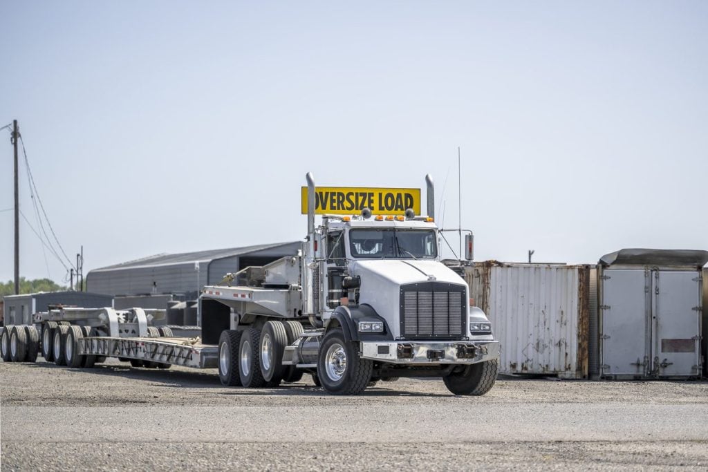 Tractor with an empty step deck trailer and oversize load sign