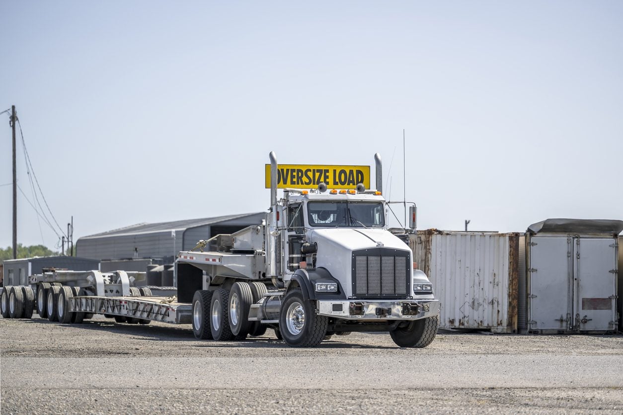 Conventional tractor with an oversize load banner and a multi axle lowboy trailer