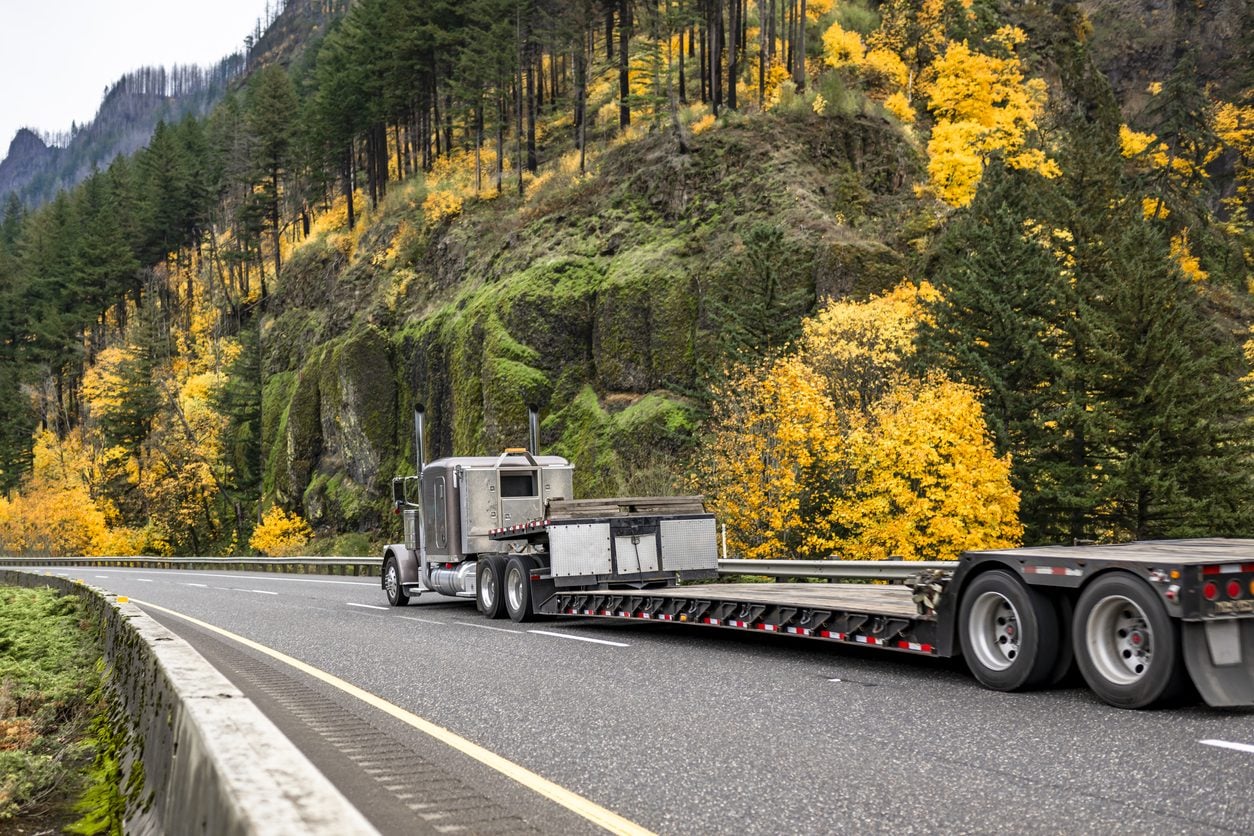 Semi truck with a step deck trailer on a mountain highway