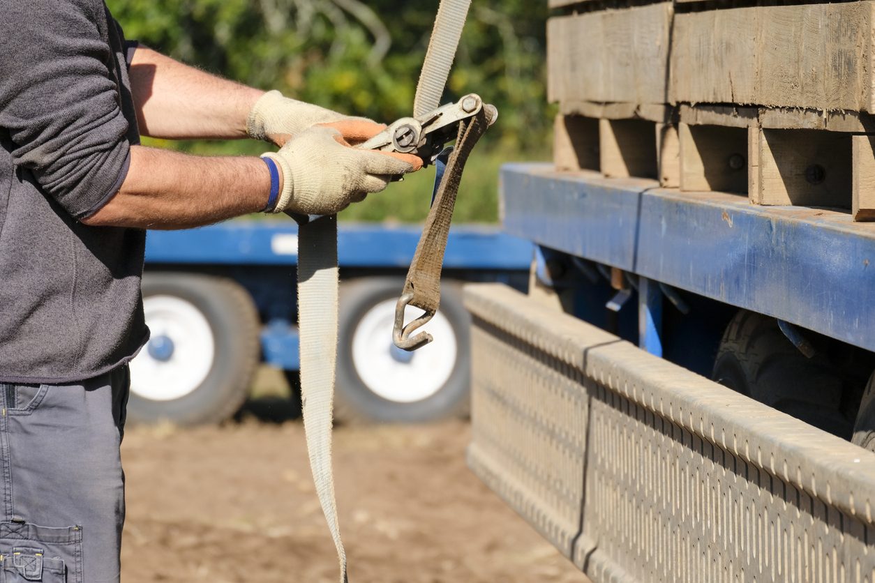 Tensioning a ratchet strap over a secured load