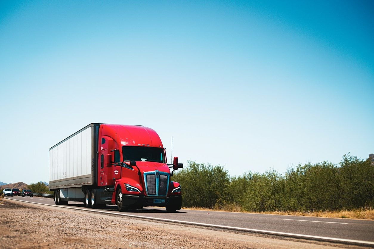 Red tractor unit hauling a trailer on a highway