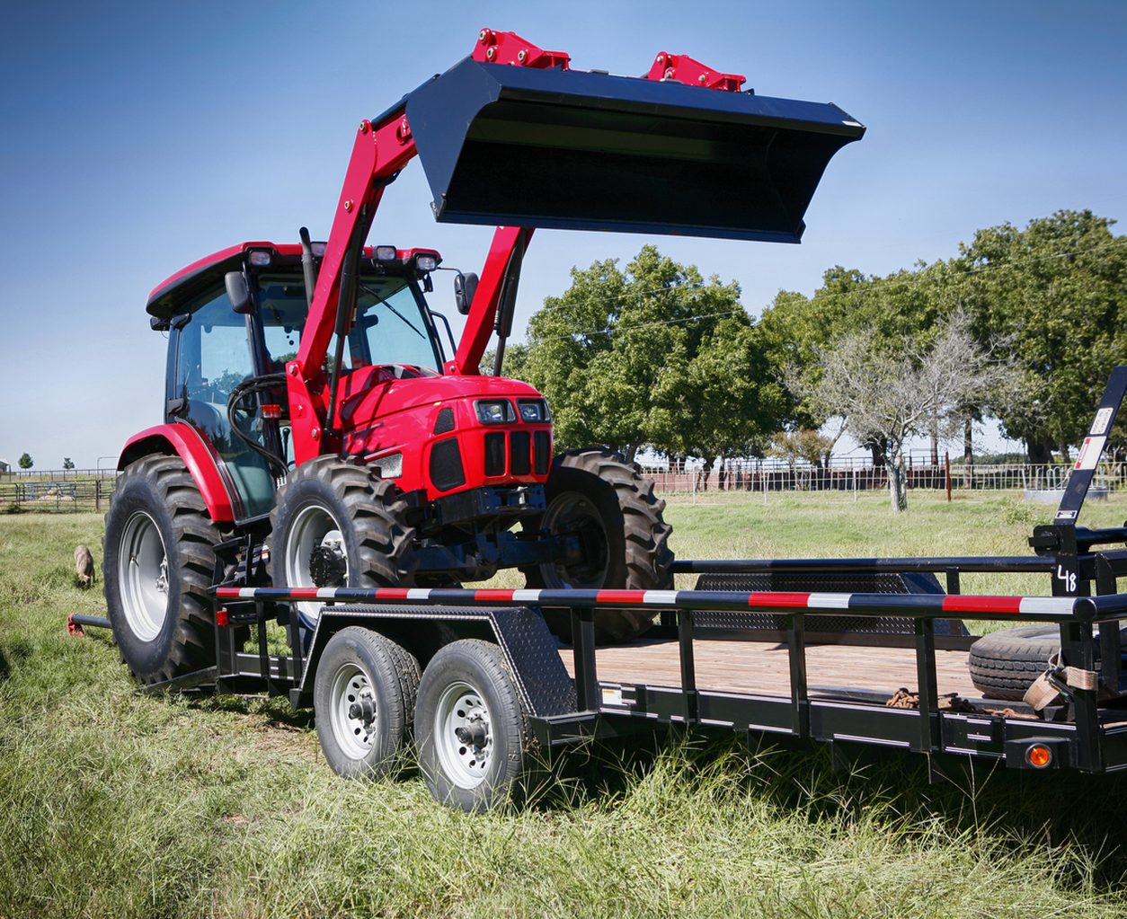 Tractor with a loader being carried on an equipment trailer