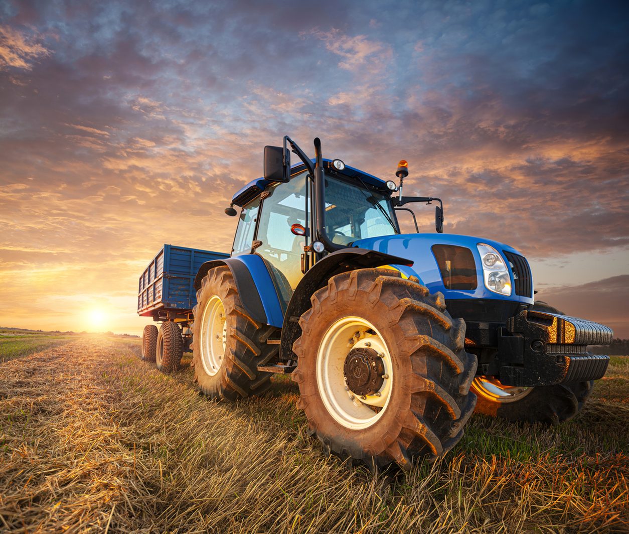 Tractor and trailer on a stubble field at sunset