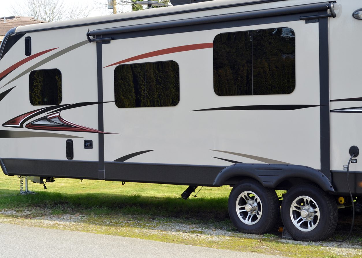 Travel trailer parked with its awning rail and wheels visible