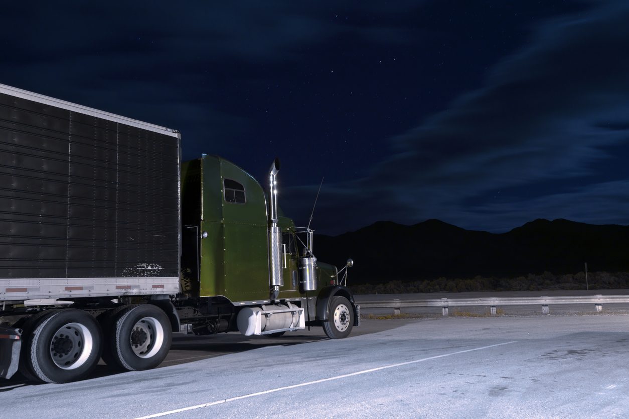 Tractor and trailer parked on a lot under a night sky