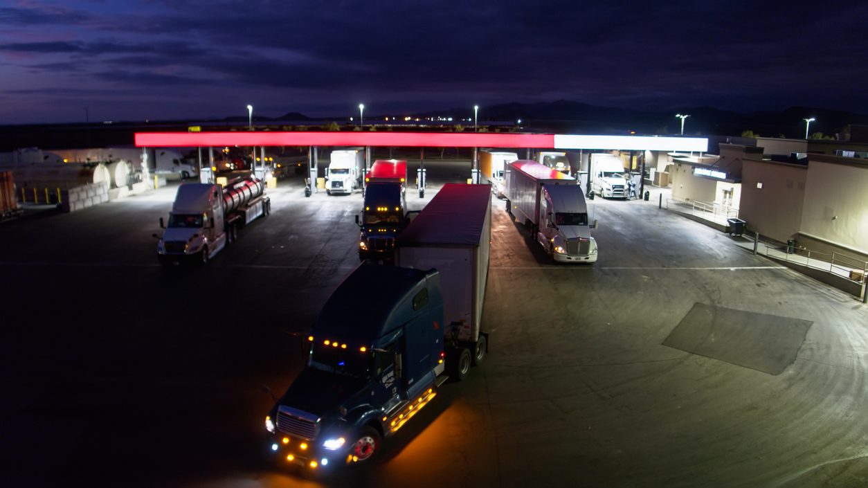 Trucks fueling under lights at a truck stop at night