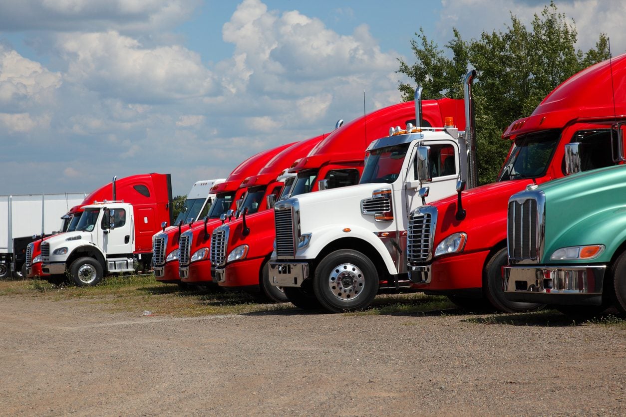 Row of red and white conventional tractors parked on a sales lot